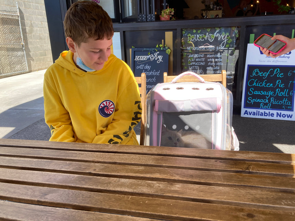 Ben and Odin are sitting near Albury in the cafe, Odin is in his pink carrier